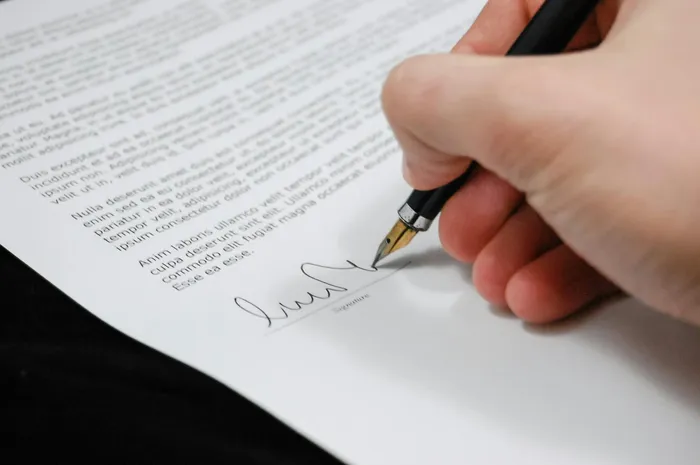 A person signing a document with a fountain pen, symbolizing acknowledgment or consent, relevant to PDF signatures and document management.